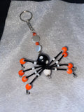 Black and white beaded spider keychain with orange accents